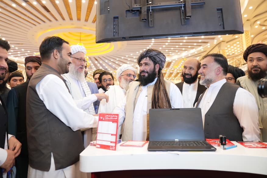 Visitors at an exhibitor service desk with a laptop and printed materials